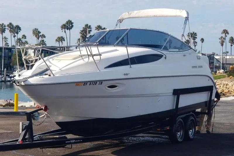 Slide: The Image of 2000 Bayliner 2655 Ciera Sunbridge boat on trailer, dockside with palm trees in background. - 16