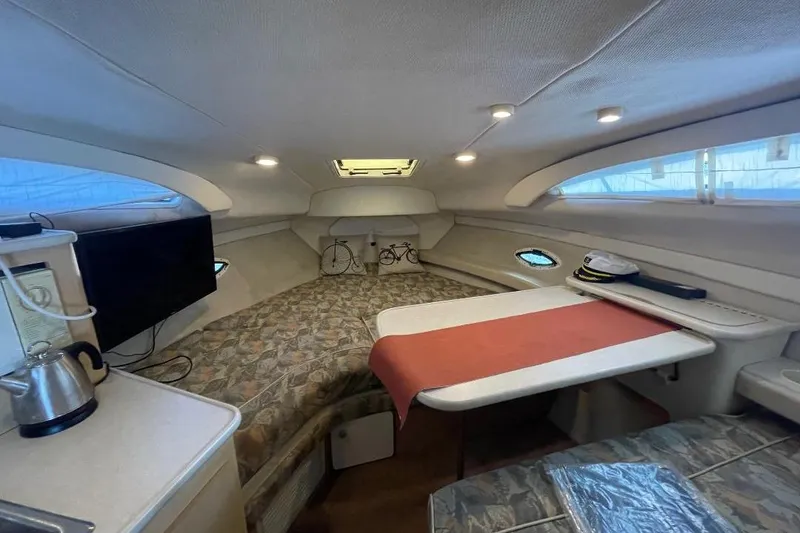 Slide: The Image of 2000 Bayliner 2655 Ciera Sunbridge cabin interior with seating, table, and kitchenette. - 4