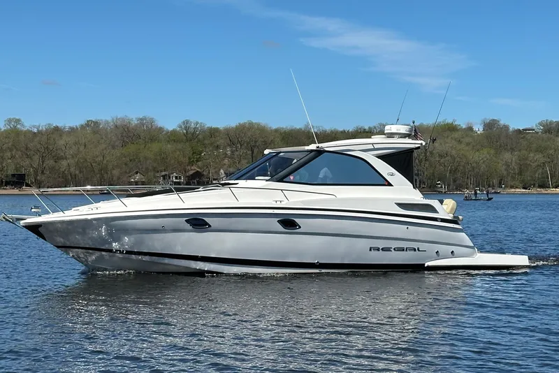 The Image of 2012 Regal 35 Sport Coupe boat cruising on a calm lake under a clear blue sky. - 0