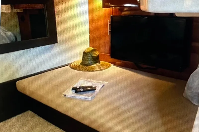 Slide: The Image of Interior of 2012 Regal 35 Sport Coupe with TV, hat, and remote on bed. - 14