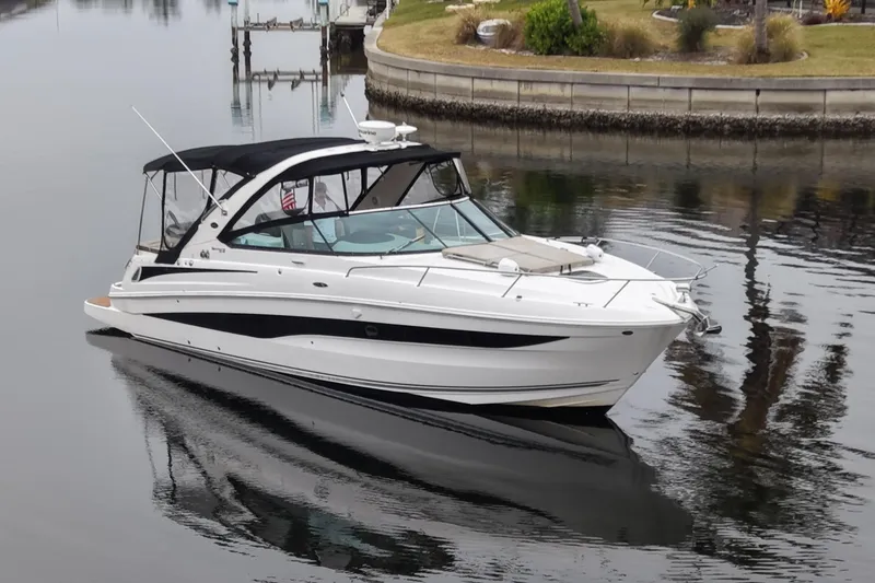The Image of 2014 Sea Ray 370 Venture boat cruising on calm waters near a marina. - 0