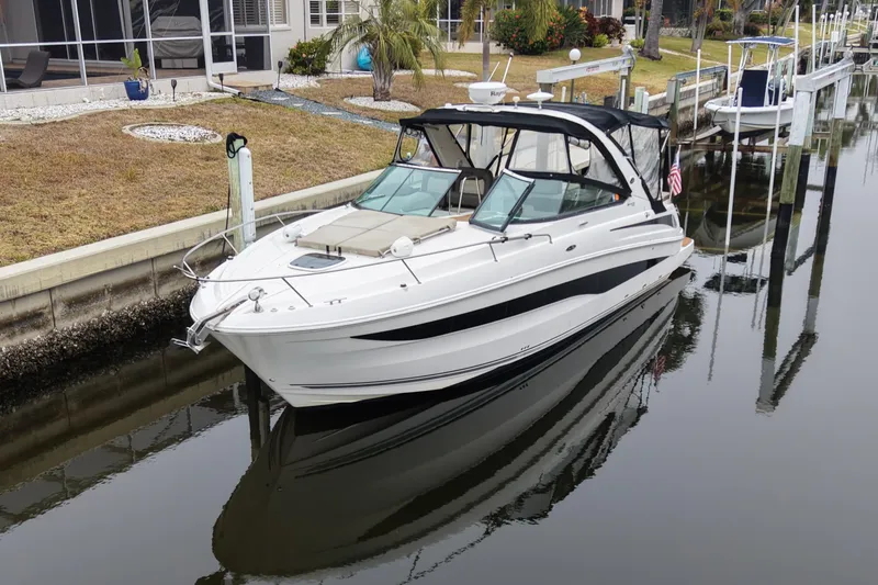 Slide: The Image of 2014 Sea Ray 370 Venture boat docked in a calm canal, reflecting in the water. - 1