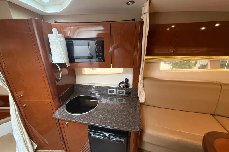 Slide: The Image of 2014 Sea Ray 370 Venture interior kitchen with microwave, stovetop, and seating area. - 18