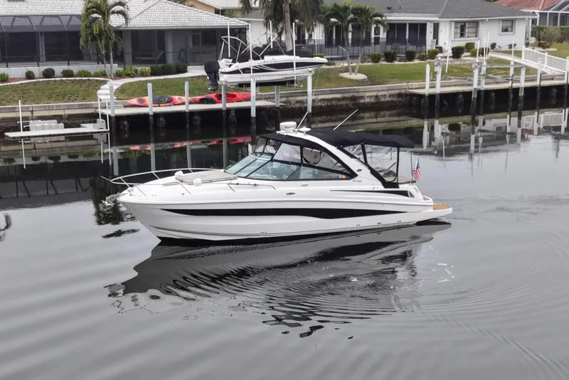 Slide: The Image of 2014 Sea Ray 370 Venture boat cruising in a calm residential canal. - 3
