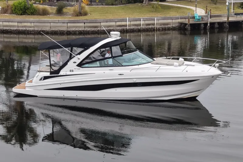 Slide: The Image of 2014 Sea Ray 370 Venture boat on calm water, featuring sleek design and black canopy. - 6