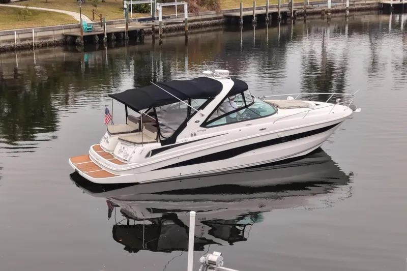 Slide: The Image of 2014 Sea Ray 370 Venture boat docked on calm water, featuring sleek design and canopy. - 7