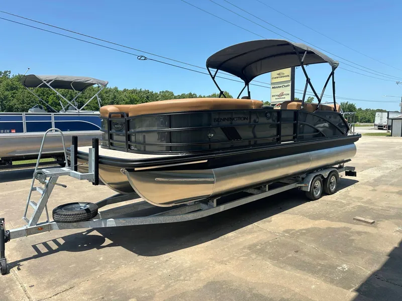 Slide: The Image of A 2026 Bennington 24 MSL pontoon boat on a trailer, featuring a black hull and brown seating. - 13