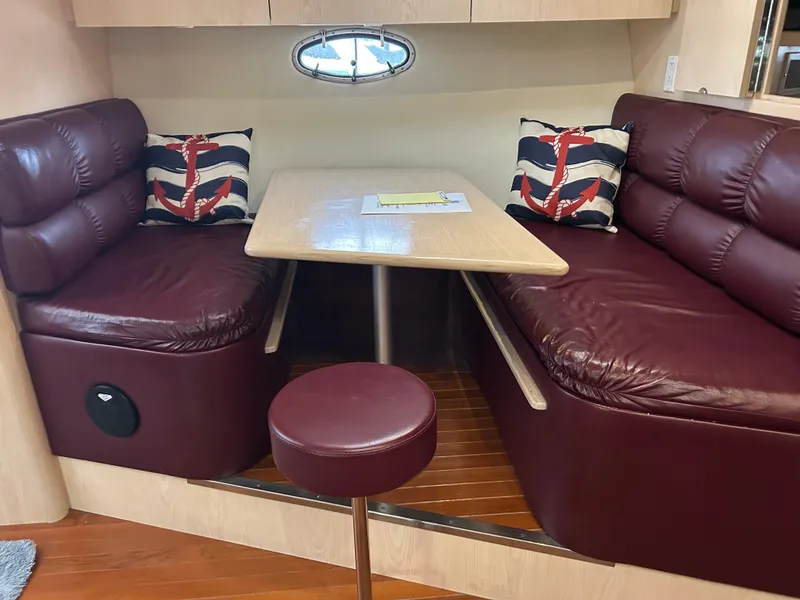 Slide: The Image of 1997 Tiara Yachts 3500 Express interior with maroon leather seating and nautical-themed cushions. - 22