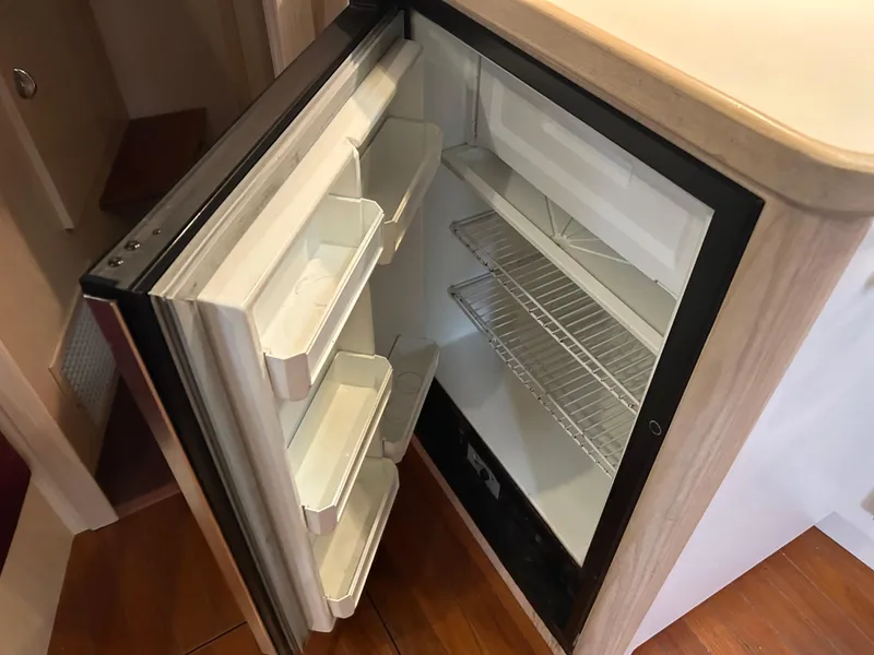 Slide: The Image of Open refrigerator inside 1997 Tiara Yachts 3500 Express, showcasing interior shelves and door compartments. - 23