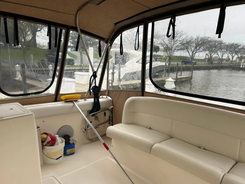 Slide: The Image of 1997 Tiara Yachts 3500 Express interior with beige seating, dockside view, and cleaning supplies. - 39