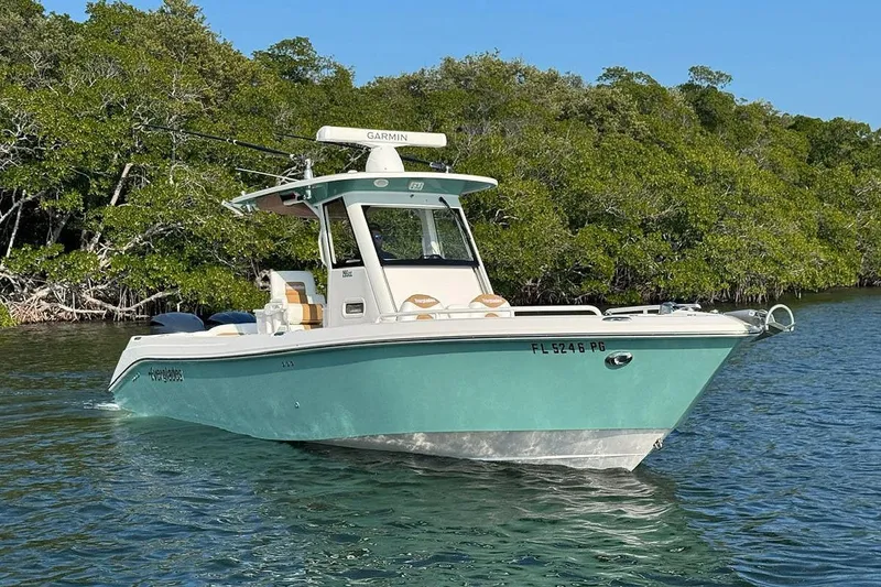The Image of 2012 Everglades 295 Center Console boat on calm water near lush greenery. - 1