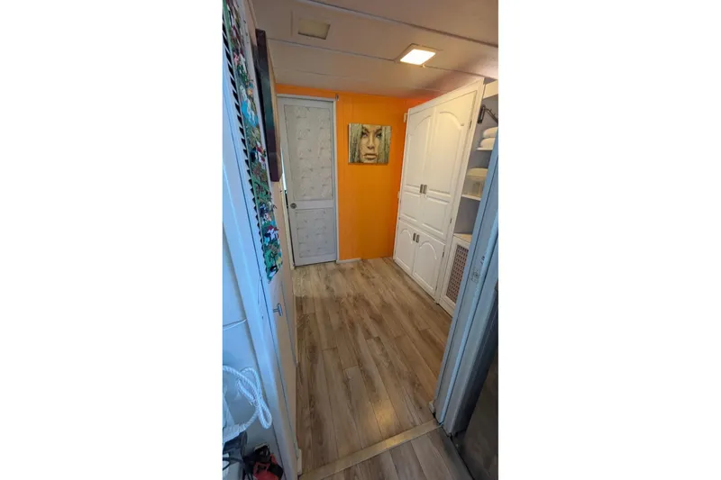 Slide: The Image of 1986 Stardust Cruisers houseboat interior with orange accent wall and wood flooring. - 10