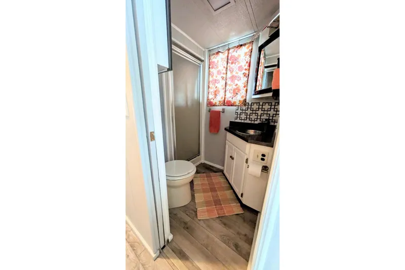 Slide: The Image of Compact bathroom in 1986 Stardust Cruisers houseboat with floral curtains and modern fixtures. - 11