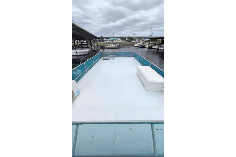 Slide: The Image of 1986 Stardust Cruisers houseboat deck with railing, docked at marina under cloudy skies. - 13
