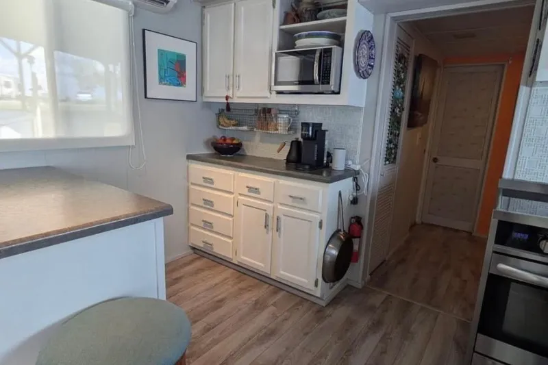 Slide: The Image of 1986 Stardust Cruisers houseboat kitchen with white cabinets, modern appliances, and wood flooring. - 7