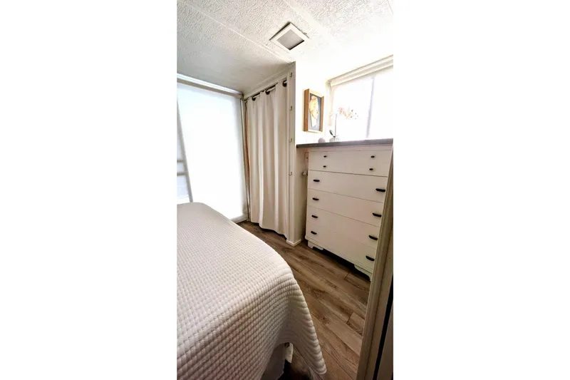 Slide: The Image of Cozy bedroom in 1986 Stardust Cruisers houseboat with white decor and wooden flooring. - 8