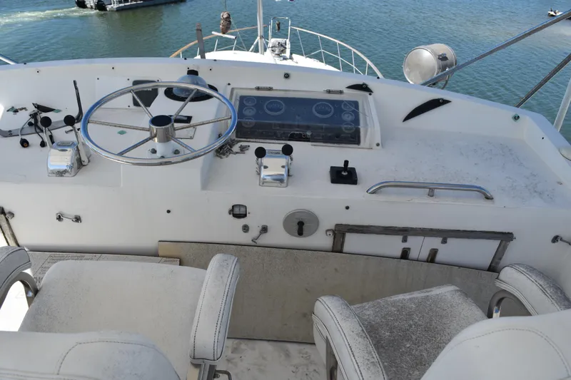 Slide: The Image of 1985 Bertram 58 Flybridge Motor Yacht helm with steering wheel and controls. - 14