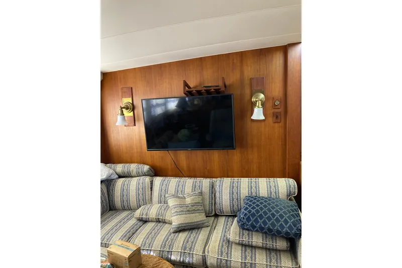 Slide: The Image of Interior of 1985 Bertram 58 Flybridge Motor Yacht with TV, striped sofa, and wall sconces. - 22