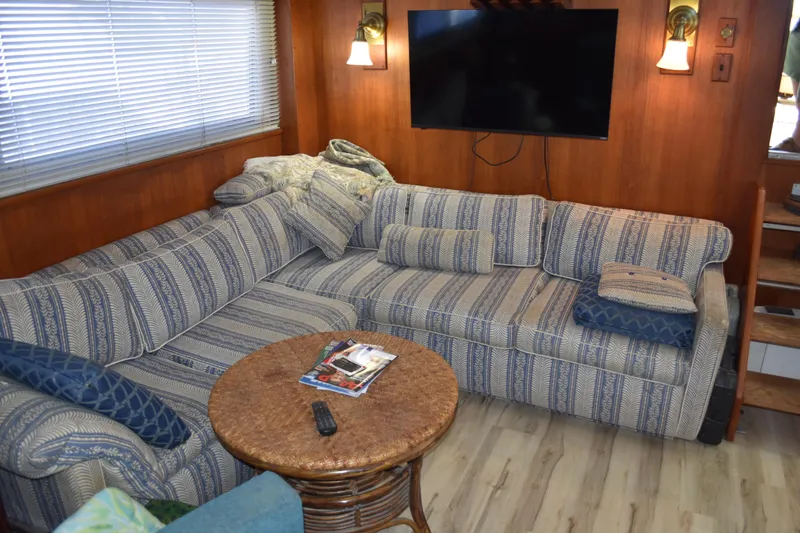 Slide: The Image of Interior of 1985 Bertram 58 Flybridge Motor Yacht with striped sofa and wall-mounted TV. - 28