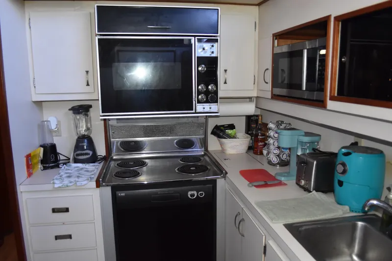 Slide: The Image of 1985 Bertram 58 Flybridge Motor Yacht kitchen with stove, microwave, and appliances. - 30