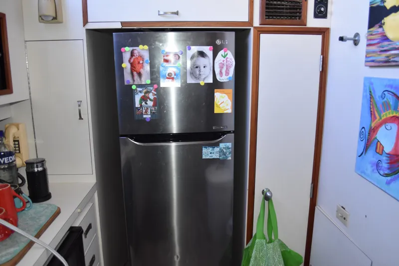 Slide: The Image of Kitchen area in a 1985 Bertram 58 Flybridge Motor Yacht with a stainless steel fridge. - 32