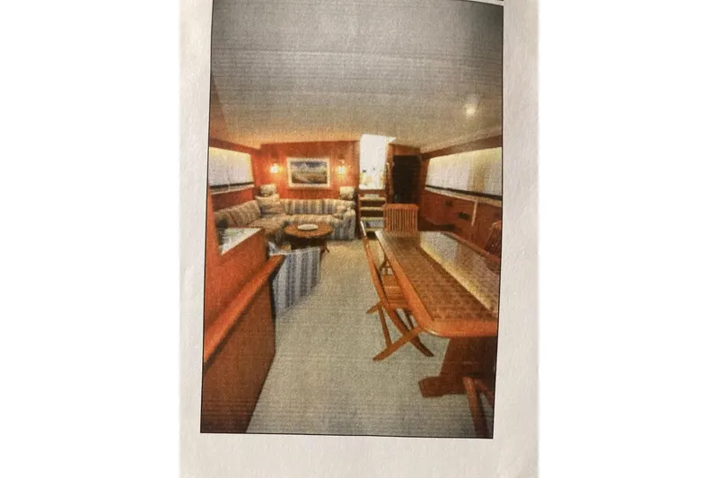 Slide: The Image of Interior of 1985 Bertram 58 Flybridge Motor Yacht, featuring elegant wood furnishings and cozy seating. - 4