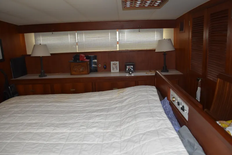 Slide: The Image of 1985 Bertram 58 Flybridge Motor Yacht bedroom with wood paneling and cozy decor. - 40