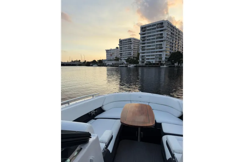 Slide: The Image of 2019 Regal 29 OBX boat on calm water at sunset, near modern buildings. - 37