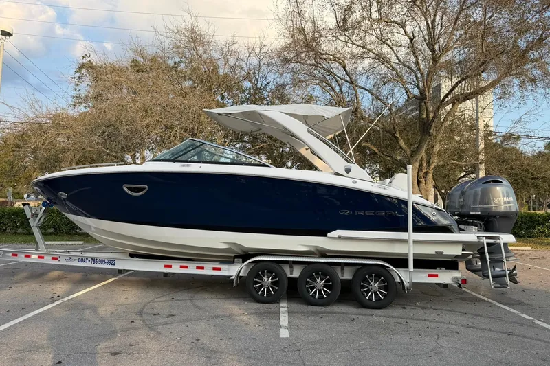 Slide: The Image of 2019 Regal 29 OBX boat on trailer, parked outdoors, featuring sleek design and Yamaha outboard engine. - 7