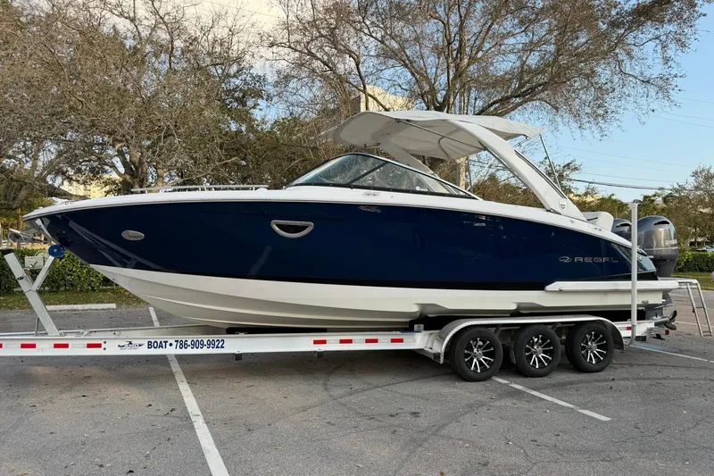 Slide: The Image of 2019 Regal 29 OBX boat on trailer, parked outdoors, showcasing sleek design and blue hull. - 8
