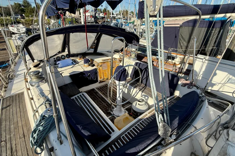 Slide: The Image of 1981 Mariner Mayflower sailboat cockpit with steering wheel, ropes, and seating at marina. - 13