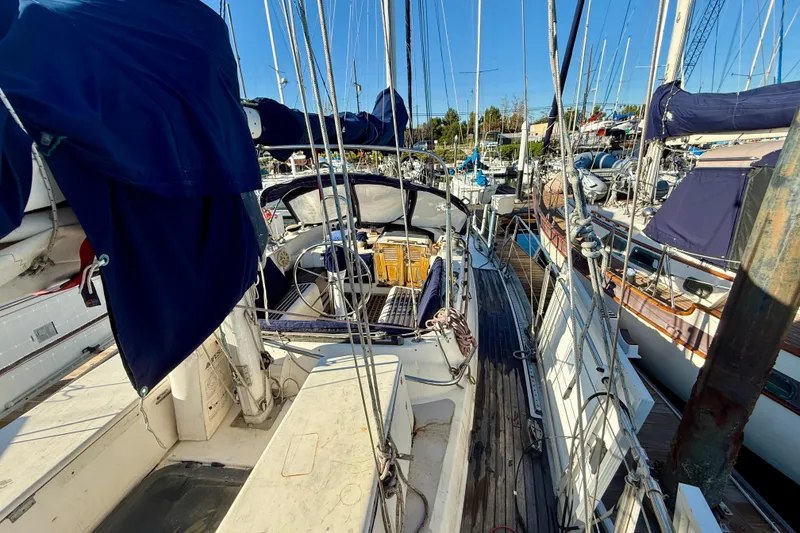 Slide: The Image of 1981 Mariner Mayflower sailboat docked at marina, featuring blue covers and wooden deck. - 15