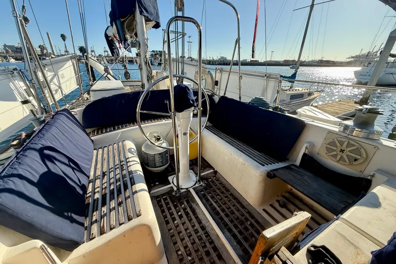 Slide: The Image of Cockpit of 1981 Mariner Mayflower sailboat with wooden seating and steering wheel, docked at marina. - 17