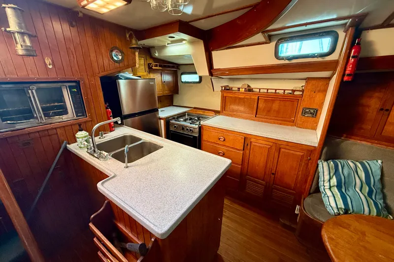 Slide: The Image of 1981 Mariner Mayflower yacht kitchen with wooden cabinetry, stainless steel appliances, and cozy seating area. - 20