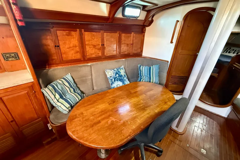 Slide: The Image of Cozy 1981 Mariner Mayflower yacht interior with wooden table, cushioned seating, and striped pillows. - 21