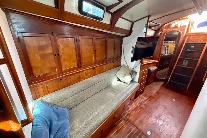 Slide: The Image of 1981 Mariner Mayflower yacht interior with wooden cabinetry, cozy seating, and mounted TV. - 23