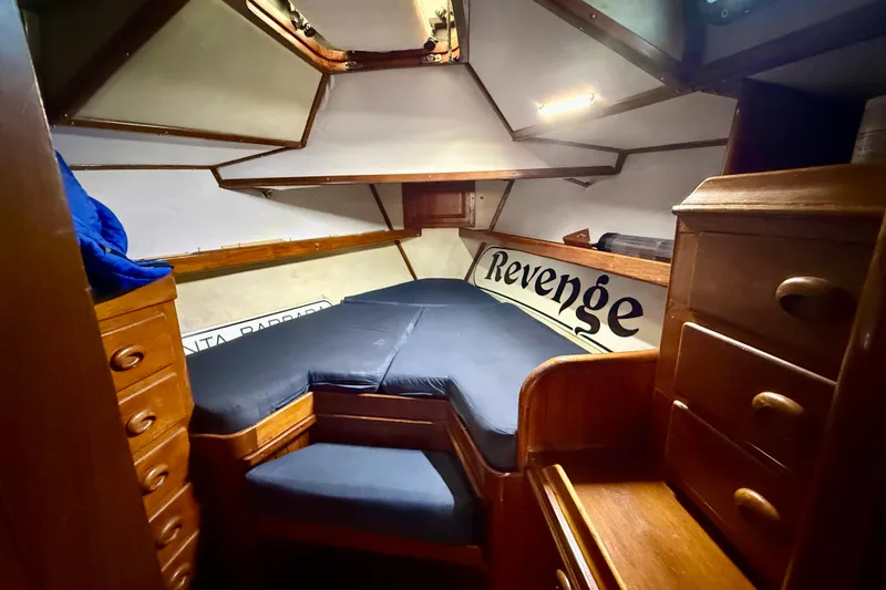 Slide: The Image of 1981 Mariner Mayflower cabin interior with wooden drawers and blue cushions. - 25
