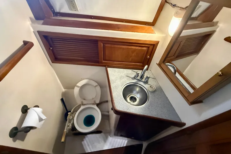 Slide: The Image of Compact 1981 Mariner Mayflower boat bathroom with sink, toilet, and wooden cabinetry. - 26