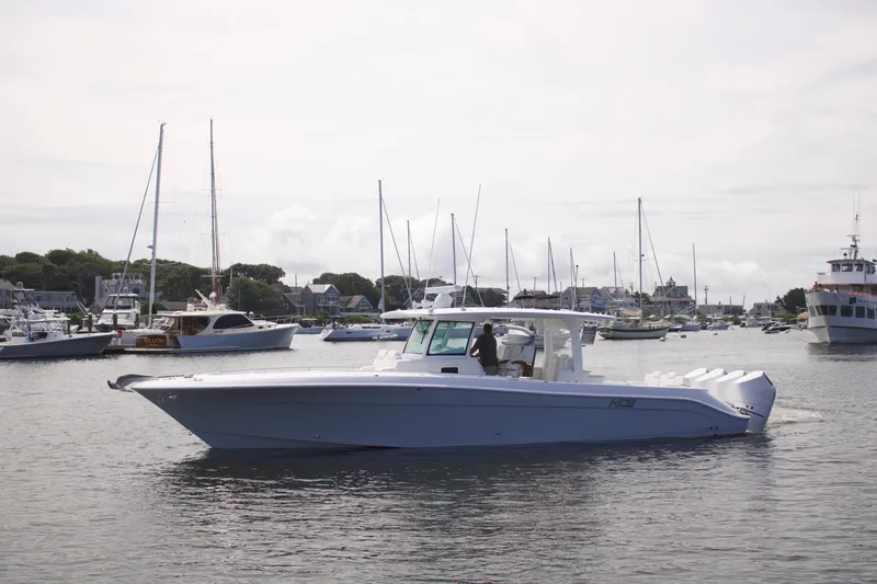 The Image of 2027 HCB 42 Lujo boat cruising in a marina with sailboats in the background. - 1
