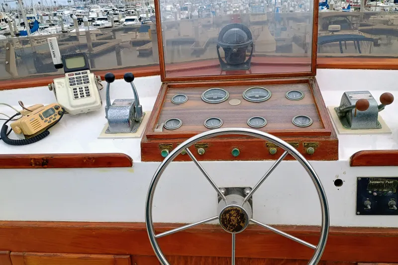 Slide: The Image of 1978 Californian LRC boat helm with steering wheel, gauges, and communication devices in a marina. - 2