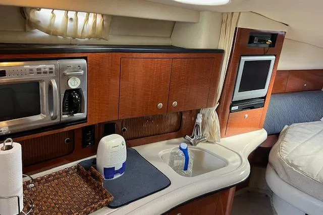 Slide: The Image of Interior of a 2005 Searay 320 boat with kitchenette and TV. - 10