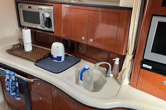 Slide: The Image of 2005 Searay 320 yacht kitchen with microwave, sink, and wooden cabinets. - 12