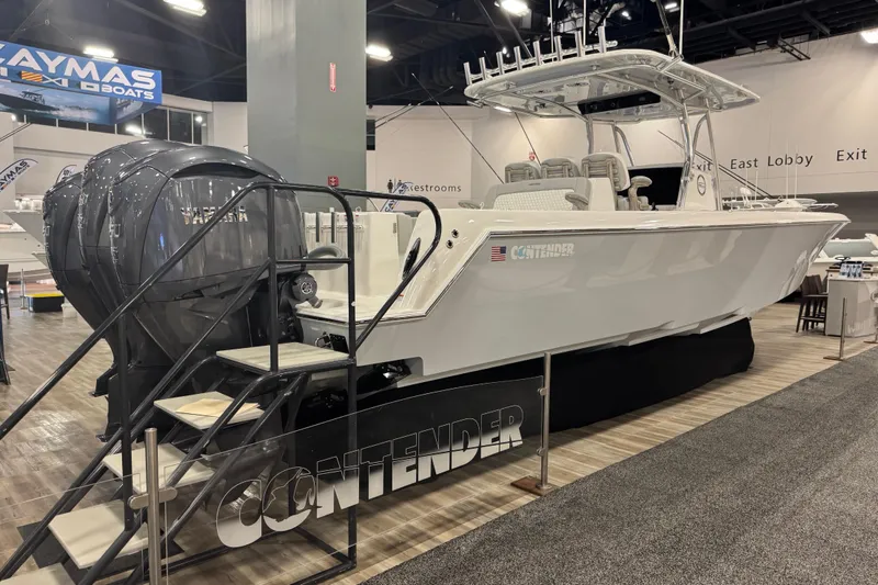 The Image of 2026 Contender 39 ST boat displayed at an indoor exhibition with triple outboard engines. - 10