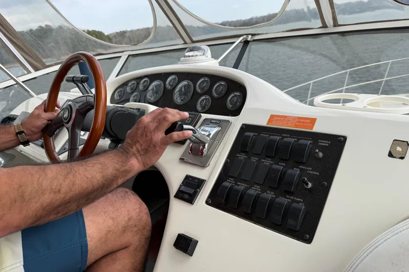 Slide: The Image of Person steering 1996 Sea Ray 420 Aft Cabin boat, focusing on dashboard controls. - 14