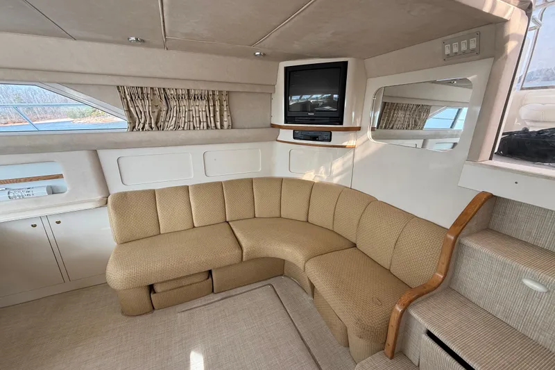 Slide: The Image of 1996 Sea Ray 420 Aft Cabin interior with beige sofa, TV, and window view. - 17