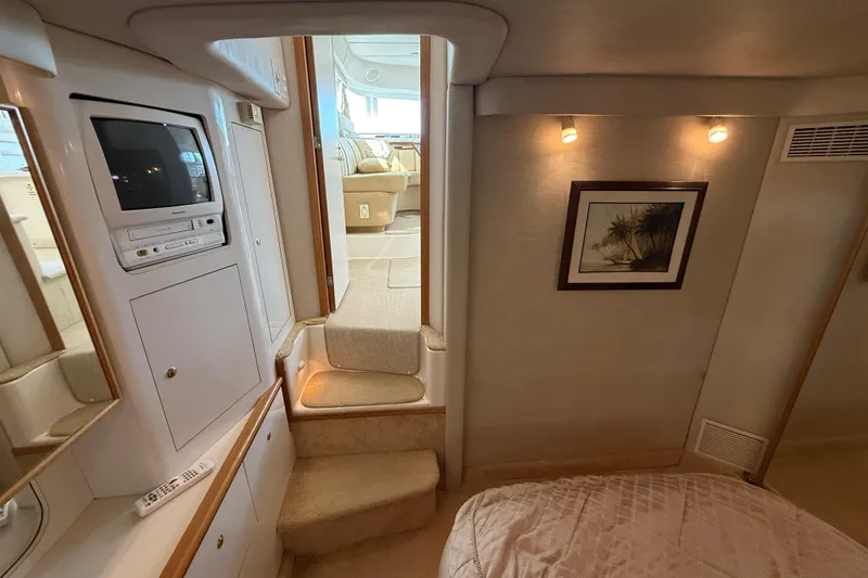 Slide: The Image of 1996 Sea Ray 420 Aft Cabin interior with TV, stairs, and cozy decor. - 22