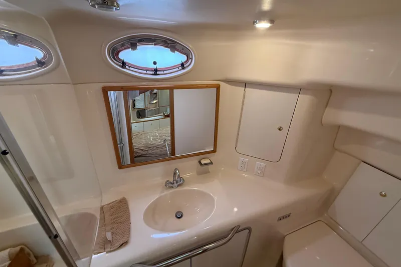 Slide: The Image of 1996 Sea Ray 420 Aft Cabin bathroom with sink, mirror, and porthole windows. - 24
