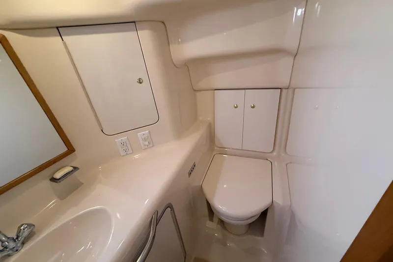 Slide: The Image of 1996 Sea Ray 420 Aft Cabin bathroom with sink, toilet, and storage cabinets. - 26