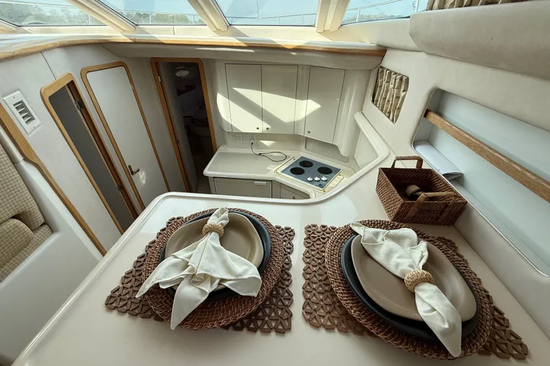 Slide: The Image of Interior of 1996 Sea Ray 420 Aft Cabin with elegant dining setup and modern kitchen. - 29