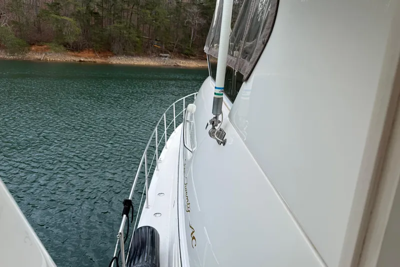 Slide: The Image of 1996 Sea Ray 420 Aft Cabin yacht docked by a serene lake shoreline. - 8